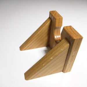 May include: A wooden stand with two angled shelves, designed to hold a record player. The stand is made of light brown wood with a natural grain.