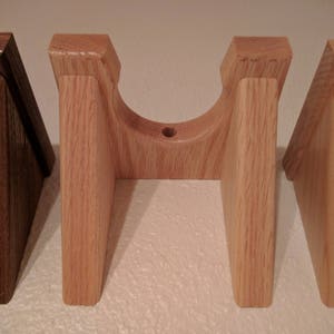 May include: Four wooden wall mounts, two are light brown and two are a darker brown. The light brown mounts have a curved top and are designed to hold a round object.