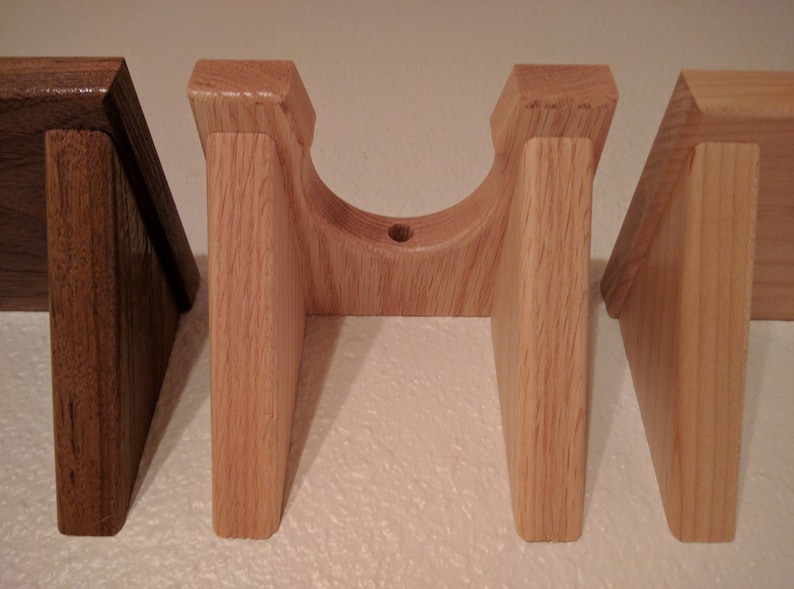 May include: Four wooden wall mounts, two are light brown and two are a darker brown. The light brown mounts have a curved top and are designed to hold a round object.