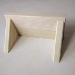 May include: A wooden stand with two triangular supports, made of light wood.
