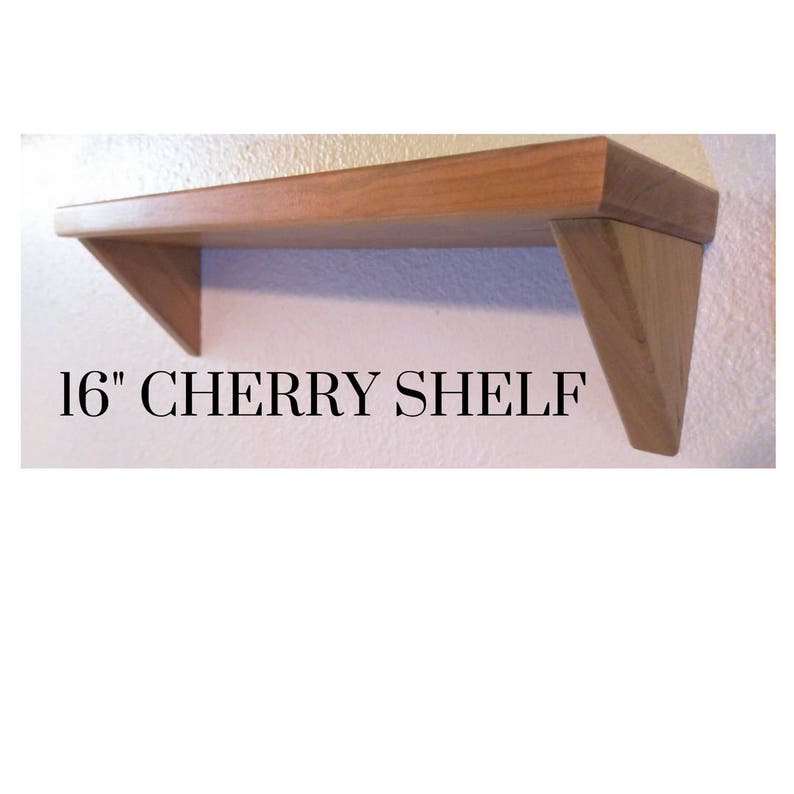 May include: A 16 inch cherry wood shelf with angled supports. The shelf is made of solid wood and has a natural finish.