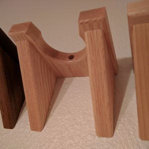 May include: Four wooden wall mounts for displaying items. The mounts are made of light brown wood and have a simple design.