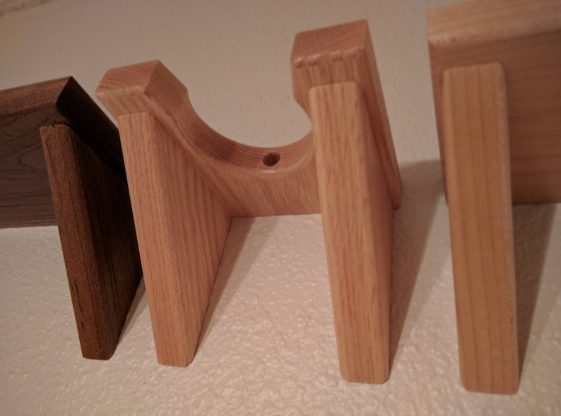 May include: Four wooden wall mounts for displaying items. The mounts are made of light brown wood and have a simple design.