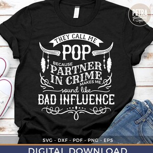 May include: Black t-shirt with white text that reads "They call me Pop because partner in crime makes me sound like bad influence". The text is surrounded by a decorative design with feathers.