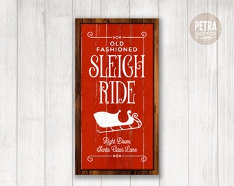 May include: A red wooden sign with white text that reads "Old Fashioned Sleigh Ride" and a white silhouette of a sleigh with the text "Right Down Santa Claus Lane".