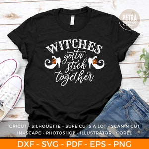Pode incluir: Camiseta preta com texto branco que diz "WITCHES gotta stick together". Duas silhuetas brancas de sapatos de bruxa de cada lado do texto. A camiseta está sobre uma superfície de madeira com tênis brancos e jeans azul.