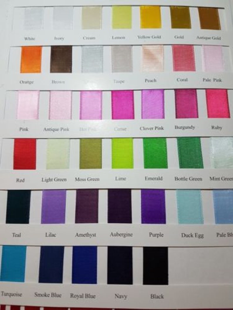 May include: A colour chart of ribbon samples with names for each colour. The colours include white, ivory, cream, lemon, yellow gold, gold, antique gold, orange, brown, taupe, peach, coral, pale pink, pink, antique pink, hot pink, carmine, clover pink, burgundy, ruby, red, light green, moss green, lime, emerald, bottle green, mint green, teal, lilac, amethyst, aubergine, purple, duck egg, pale blue, turquoise, smoke blue, royal blue, navy, and black.