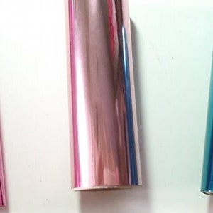 May include: Three rolls of metallic wrapping paper. The rolls are pink, rose gold, and teal.