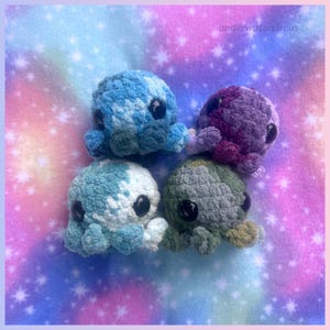 May include: Four small, round, crocheted octopus plushies with large black plastic eyes. One is blue and white, one is solid blue, one is purple and dark pink, and one is olive green. The text underwatercircus is visible in the top right corner.
