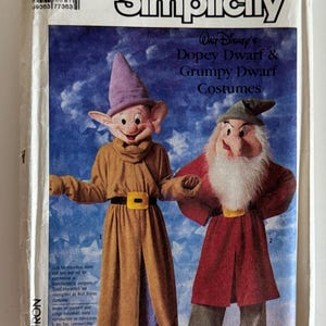 May include: A Simplicity sewing pattern envelope for Walt Disney's Dopey Dwarf and Grumpy Dwarf costumes. The cover features illustrations of two characters wearing long tunics, belts with yellow buckles, and pointed hats against a blue star background.