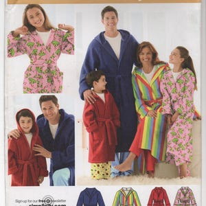 May include: Simplicity easy-to-sew pattern featuring hooded robes in various colors and patterns. The robes include a solid navy blue, a rainbow striped, a solid red, and a pink robe with a green frog pattern. The pattern size is A XS-L/XS-XL.