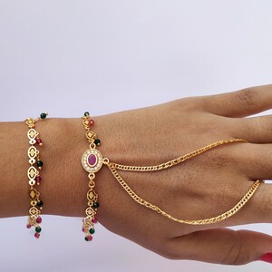 Pulsera tradicional de panja dorada de forma ovalada en conjunto con hermosos cristales transparentes rosas y verdes colgando y diamantes americanos tachonados