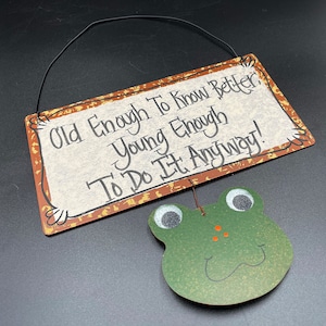 Metal Frog Sign says Old Enough to Know Better, Young Enough to Do It Anyway! / Hanging Tin Sign with Dangling Frog Face