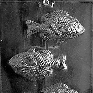 May include: A black and white mold for making chocolate fish. The mold has three fish shapes, each with a detailed design.