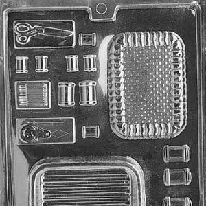 May include: A black and white plastic mold for making chocolate sewing themed treats. The mold features a pair of scissors, spools of thread, a needle and thread, a thimble, a button, and a small basket.