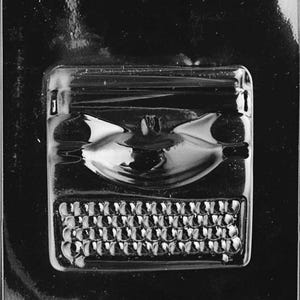 May include: A clear plastic mold for making chocolates. The mold features a bat design and a keyboard, with the text "LIFE OF THE PARTY OS..." at the bottom. Ideal for themed treats.