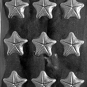 Puede incluir: Un molde de plástico negro con nueve cavidades en forma de estrella de mar. Cada estrella de mar tiene superficies texturizadas detalladas. El molde está diseñado para crear artículos decorativos, posiblemente para manualidades o confitería.