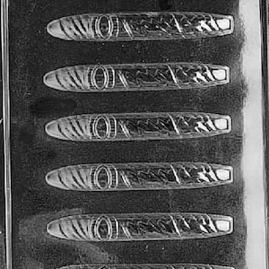 Può includere: Uno stampo in plastica trasparente contenente sei cavità a forma di sigaro. Ogni cavità presenta un design dettagliato, tra cui una fascia al centro e un'estremità rettangolare. Lo stampo è per dolci.