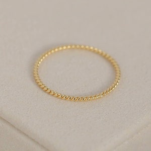 May include: A simple gold ring with a twisted band.