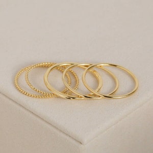 May include: Set of four gold-toned stacking rings. The rings are simple and delicate, with a smooth finish.