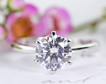 May include: A silver engagement ring with a large, clear, round-cut diamond.