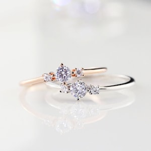 May include: Two delicate rings with a cluster of small diamonds set in a silver and rose gold band.