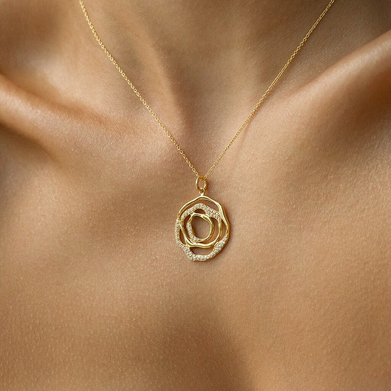 May include: A gold necklace with a circular pendant featuring a layered design of three overlapping circles, each set with small sparkling diamonds.
