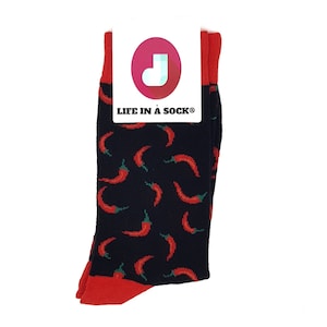 Può includere: Un paio di calzini neri con un motivo a peperoncino rosso. I calzini hanno un polsino rosso e il nome del marchio "LIFE IN A SOCK" è stampato su un'etichetta bianca attaccata ai calzini.