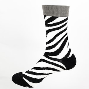 May include: A pair of black and white zebra print socks with a grey cuff.