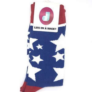 以下が含まれることがあります： 白の星柄の青と赤の靴下です。靴下には「LIFE IN A SOCK」というタグが付いています。