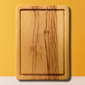 May include: A rectangular wooden cutting board with a natural wood grain finish. The board has a raised edge around the perimeter.