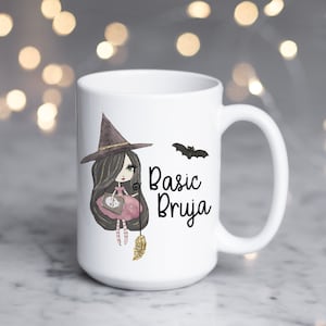 Könnte beinhalten: Weiße Keramiktasse mit einer Comic-Hexe, die einen Besen und eine Tasche hält. Die Tasse hat schwarzen Text mit der Aufschrift "Basic Bruja" und eine schwarze Fledermaus-Illustration.