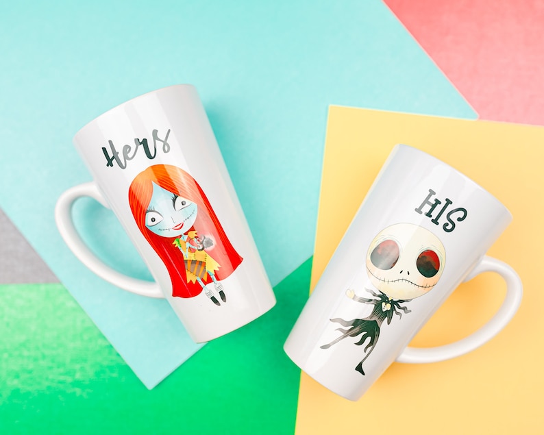 Może przedstawiać: Dwa białe ceramiczne kubki z kresk&oacute;wkowym wzorem. Jeden kubek ma postać z czerwonymi włosami z napisem "Hers". Drugi kubek ma postać w czerni i bieli z napisem "His".