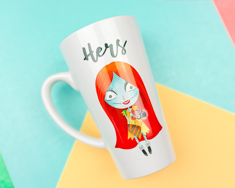 Może przedstawiać: Biały kubek ceramiczny z postacią z kresk&oacute;wki o czerwonych włosach trzymającą mniejszą postać z kresk&oacute;wki. Na kubku napisano &bdquo;Hers&rdquo; czarnym kolorem.