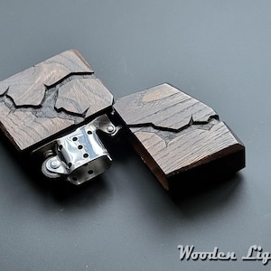 May include: A wooden lighter with a dark brown finish and a carved design. The lighter is open, revealing the metal mechanism inside.