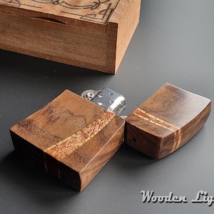 May include: A wooden lighter with a dark brown finish and a lighter insert. The lighter is made of two pieces that fit together. The lighter has a wood grain pattern and a thin line of lighter wood running along the edge.