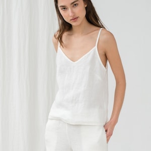 Peut inclure: Un haut de réservoir en lin blanc et un pantalon assorti. Le haut de réservoir a un col en V et le pantalon a des poches.