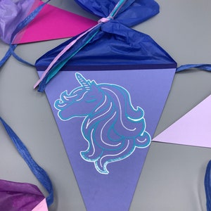 Pu&ograve; includere: Striscione triangolare viola e blu con una silhouette di testa di unicorno al centro. L'unicorno ha un corno d'argento e una criniera blu. Lo striscione &egrave; legato con un nastro blu.
