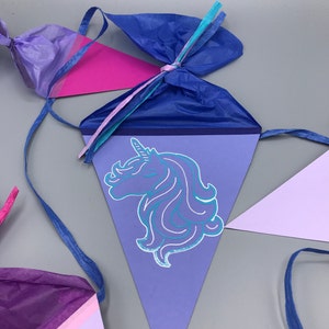 Pu&ograve; includere: Uno striscione triangolare viola e rosa con un'illustrazione di unicorno blu. Lo striscione &egrave; decorato con nastri blu, rosa e turchese.