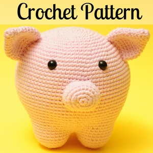 May include: A pink crocheted pig amigurumi toy with black eyes. The pig has a small, round snout and small, rounded ears.