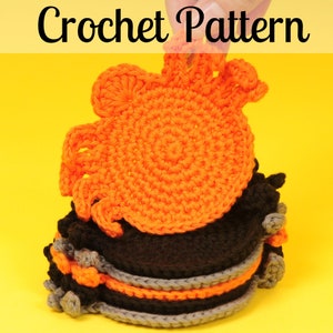 May include: A stack of handmade crochet coasters in black, grey, and orange, topped with an orange crab design. The image includes the text "Crochet Pattern". These coasters are likely part of a craft project.