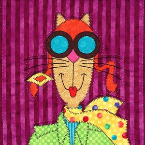Op de afbeelding: Een grillige patchworkkat met een groene jas, een gele sjaal met witte stippen en een bril. De kat heeft een roze neus en een rode mond. De achtergrond is een paars-wit gestreepte stof.