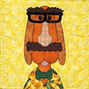 Peut inclure: Un chien brun avec un nez à carreaux, des lunettes noires, une moustache brune et un nœud papillon vert porte une chemise à fleurs jaune et verte. Le chien est sur un fond jaune avec des tourbillons blancs.