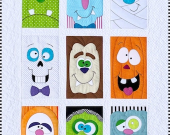 Puede incluir: Un edredón con temática de Halloween con nueve caras de monstruos coloridos. Cada monstruo tiene rasgos únicos, incluyendo piel verde, azul y naranja, y diversas expresiones faciales. El edredón tiene un fondo blanco con un borde a rayas blancas y negras.