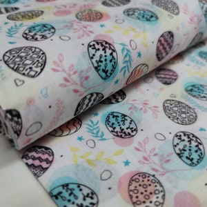 Könnte beinhalten: Weißer Stoff mit einem sich wiederholenden Muster aus bunten Ostereiern mit schwarzen Umrissen. Die Eier haben verschiedene Designs und sind von kleinen Zweigen und Sternen umgeben.