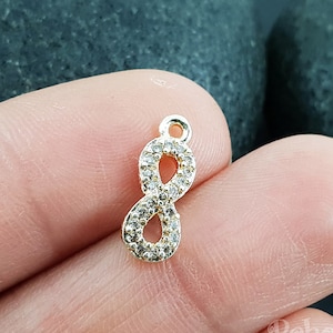 Könnte beinhalten: Goldener Unendlichkeits-Anhänger mit klaren Strasssteinen. Der Anhänger ist ein beliebtes Symbol für Ewigkeit und unendliche Liebe.