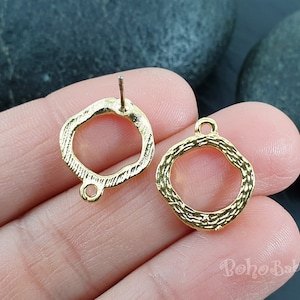 Könnte beinhalten: Zwei goldfarbene Ohrringrohlinge aus Metall mit einem strukturierten, seilartigen Design. Die Ohrringrohlinge haben die Form eines Kreises mit einer leicht unregelmäßigen Form. Die Ohrringrohlinge befinden sich auf einer Hand.