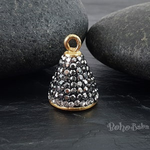 May include: Gold-tone cone-shaped pendant charm with a black rhinestone design. The charm has a loop at the top for attaching to jewellery.