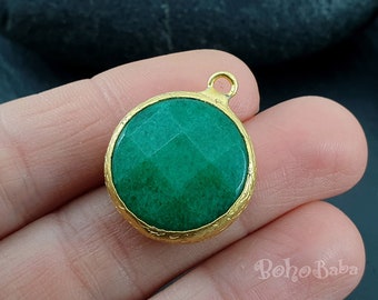 May include: A round green gemstone pendant with a gold-toned setting. The pendant has a smooth, polished surface and a slightly textured edge.