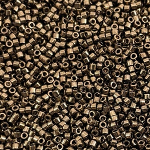 Puede incluir: Una imagen de primer plano de una gran cantidad de pequeñas cuentas redondas y metálicas. Las cuentas son de color bronce oscuro y tienen un acabado brillante.